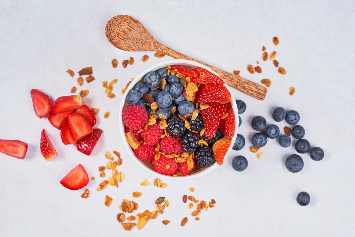 red strawberries and blue berries on white ceramic bowl